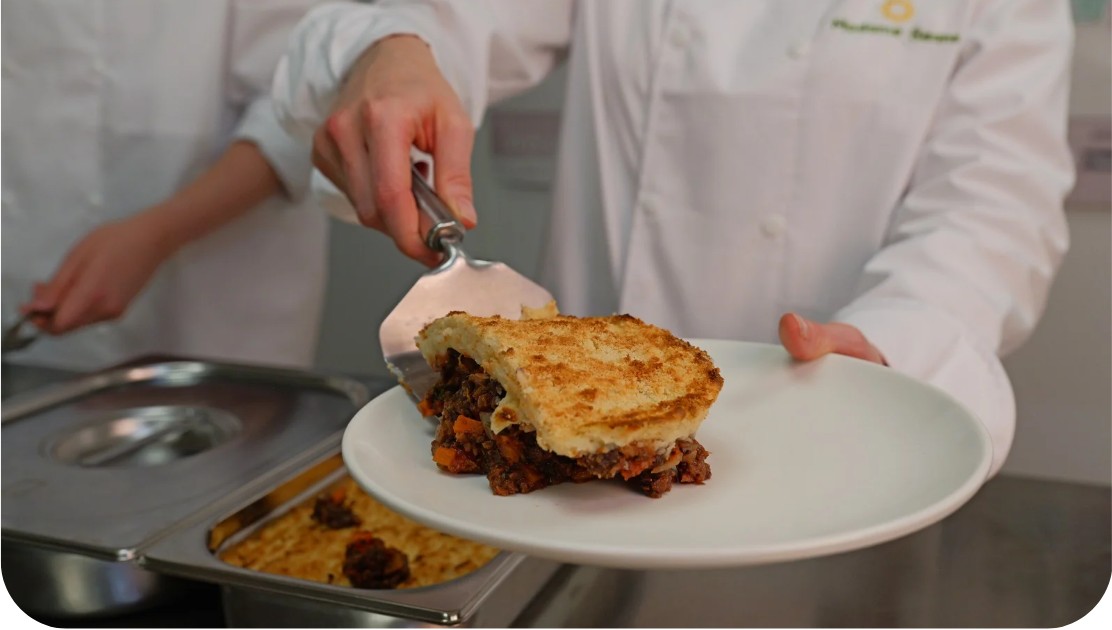 Cuisinière servant une part de tourte aux légumineuses